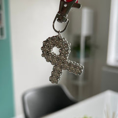 Silver keychain with a ribbon design held up by a hand.