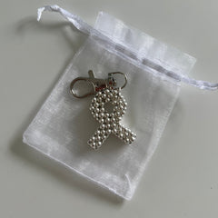 Silver keychain made of small silver beads laid on a clear drawstring bag